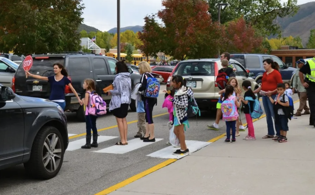 Image of adults helping students through traffic at a school cross walk